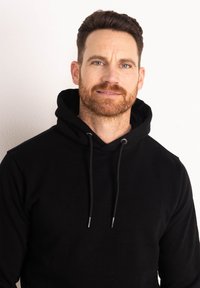 Felpa nera con cappuccio realizzata in tessuto morbido, con un design semplice e texture non decorata. Sfondo neutro.