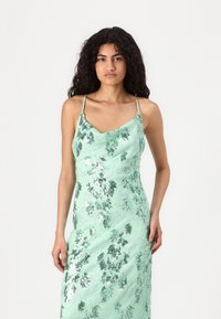 Glänzendes mintgrünes Kleid mit einem cowl Ausschnitt, dünnen Trägern und Pailletten-blumigen Mustern. Figurnaher Schnitt, strukturiertes Material.