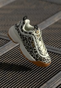 Leopard print sneaker with a white and beige mesh upper, contrasting brown sole, and prominent branding on the side.