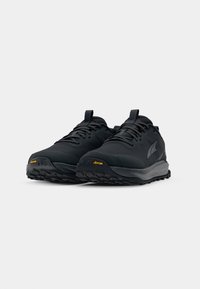 Baskets de course noires avec une tige texturée, fermeture à lacets, talon renforcé et logo Vibram sur la semelle en caoutchouc, avec un motif de semelle robuste.