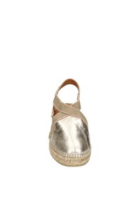 Metallic gold espadrille with beige fabric cross-strap. Features a round toe and jute rope sole, showcasing a smooth texture with subtle sheen.