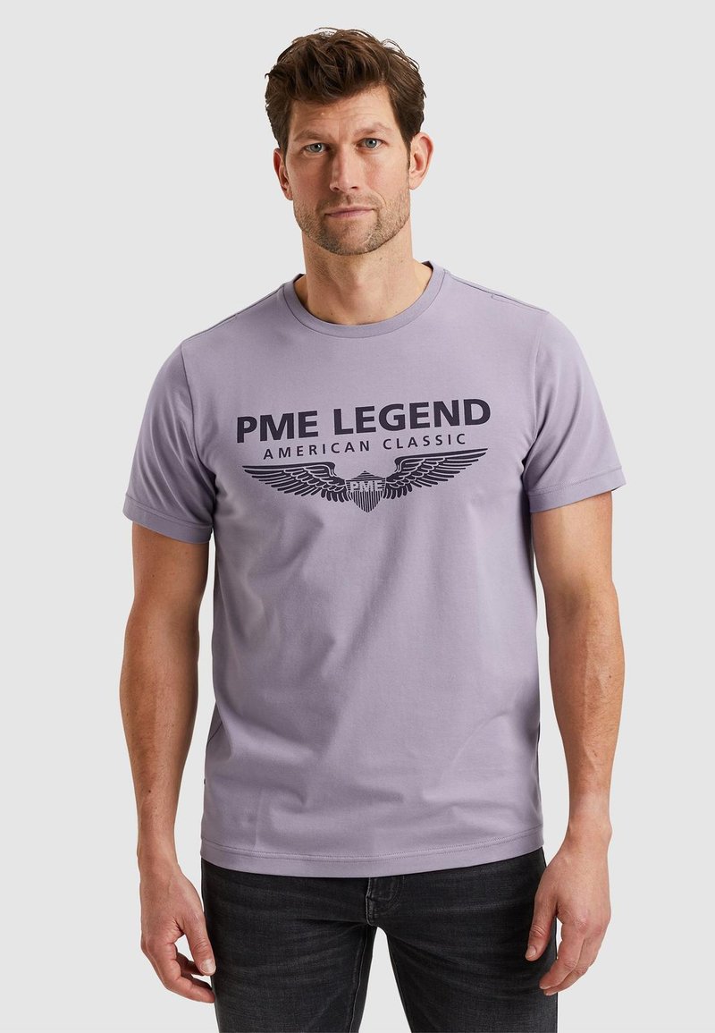 Fialové tričko vyrobené z bavlny, s potiskem černého loga s křídly a textem "PME LEGEND AMERICAN CLASSIC" na přední straně.
