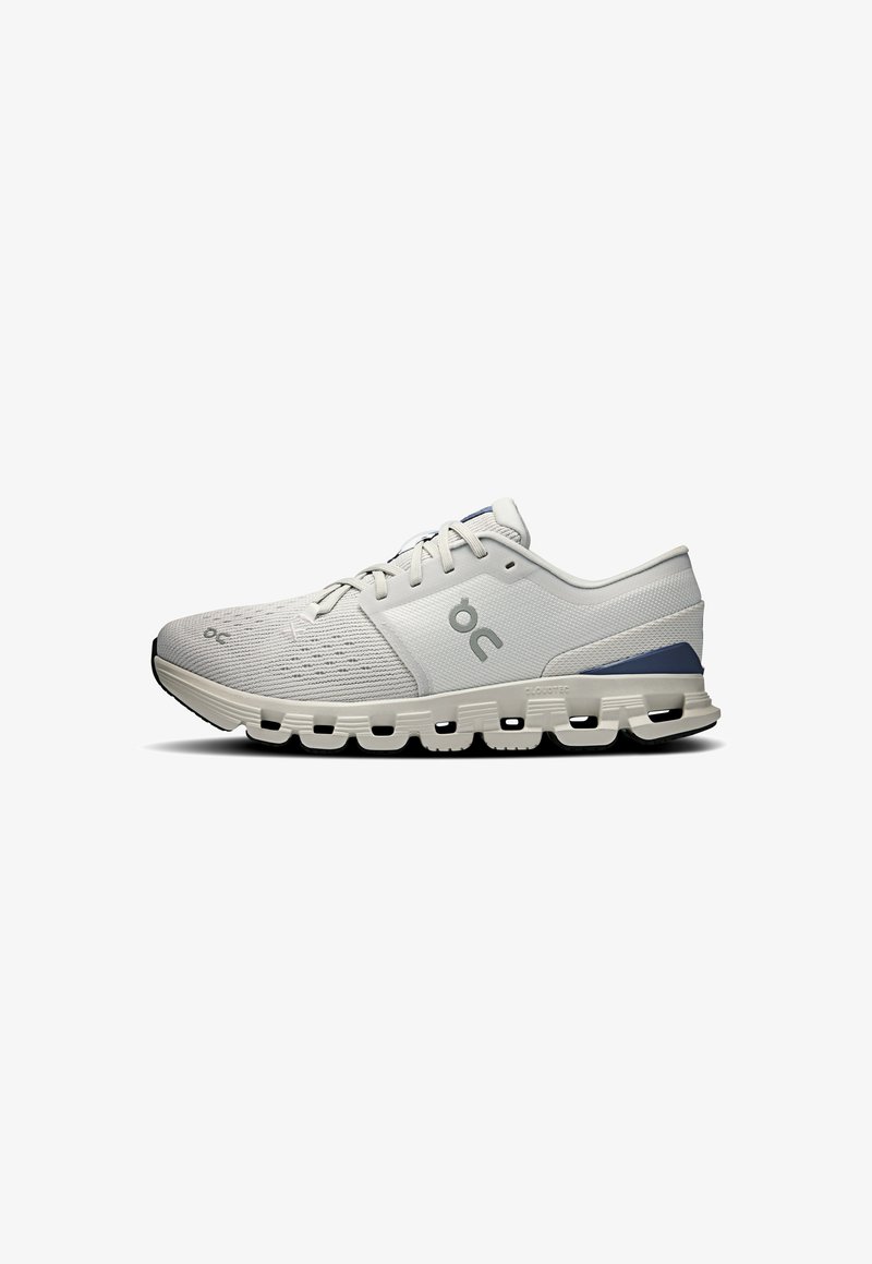 Light gray athletic shoe with a textured upper, lace design, and cushioned sole featuring multi-shaped cutouts. Accent in darker gray.