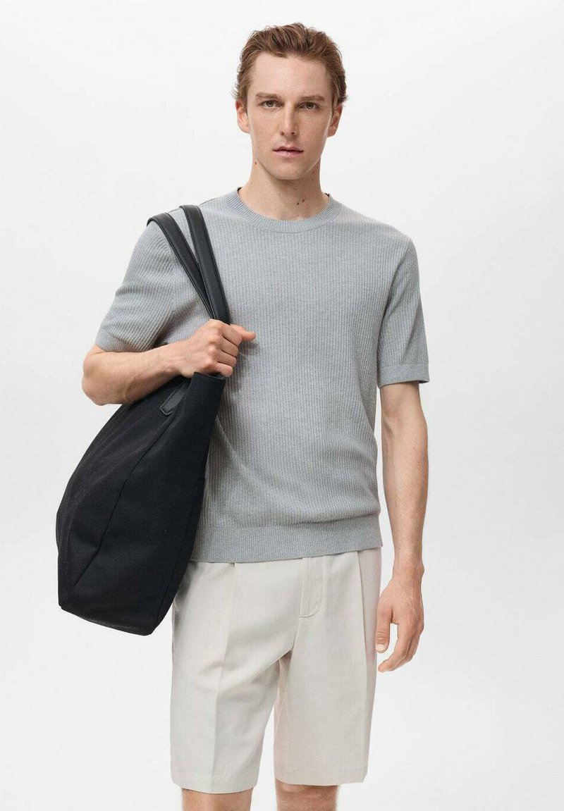 Gray ribbed knit shirt, cream shorts, and a large black tote bag with a soft texture and long shoulder straps. Simple and modern design.
