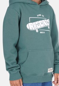 Grüne Kapuzenjacke aus weichem Stoff mit einem weißen Grafikdruck im Skateboard-Design. Vordertasche im Kängurustil und gerippte Bündchen.