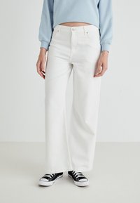 Witte wijde jeans van katoen denim, met een hoge taille, zijzakken en een eenvoudige uitstraling, gecombineerd met zwarte sneakers.