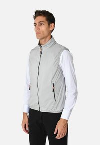 Gilet senza maniche grigio chiaro con colletto alto, frontale con zip, due tasche laterali e tirazip arancioni. Presenta una texture liscia e lucida.