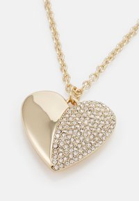 Kuldne südame ripats kaelakee, mille üks pool on sile ja läikiv, teine pool on kaunistatud selgete rhinestone'idega, mis on seotud ahelaga.