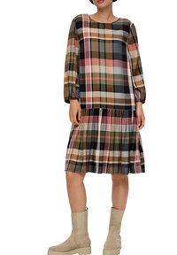 Gecontroleerde jurk met lange mouwen, in groen, bruin, roze en crème. Heeft een geraffineerde taille en een knielange zoom. Draagt met beige enkellaarsjes.