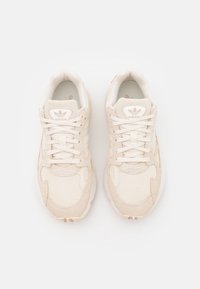Beige Adidas-sneakers med en strukturerad mesh och ovandel i mocka, med snörning, vadderad krage och logotyp på tungan.