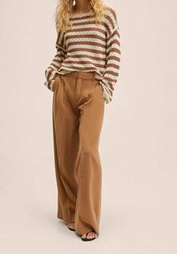 Gestreifter Strickpullover in Off-White und Braun, kombiniert mit hochtaillierten, weiten, braunen Hosen. Glattes Material und lockere Passform.