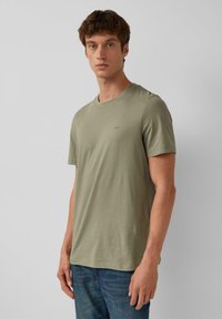 Olivenfarbene Baumwoll-T-Shirt mit rundem Halsausschnitt und kurzen Ärmeln. Verfügt über ein kleines, dezentes Logo auf der Brust und eine normale Passform.