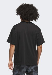 Sort kortærmet t-shirt med en glat tekstur, løs pasform og rund halsudskæring. Designet er enkelt uden synlige mønstre eller accenter.