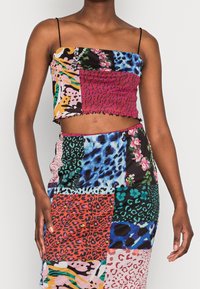 Färggängig tvådelad set med en kort topp med spaghettiband och en figurnära kjol, båda i olika djurtryck och livfulla färger.
