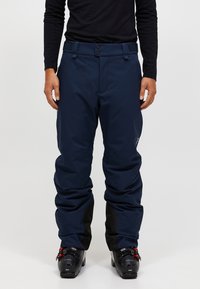 Marineblauwe skibroek met een losse pasvorm, voorzien van een gladde textuur, verstelbare taille met klittenband en zwarte accenten bij de enkels.