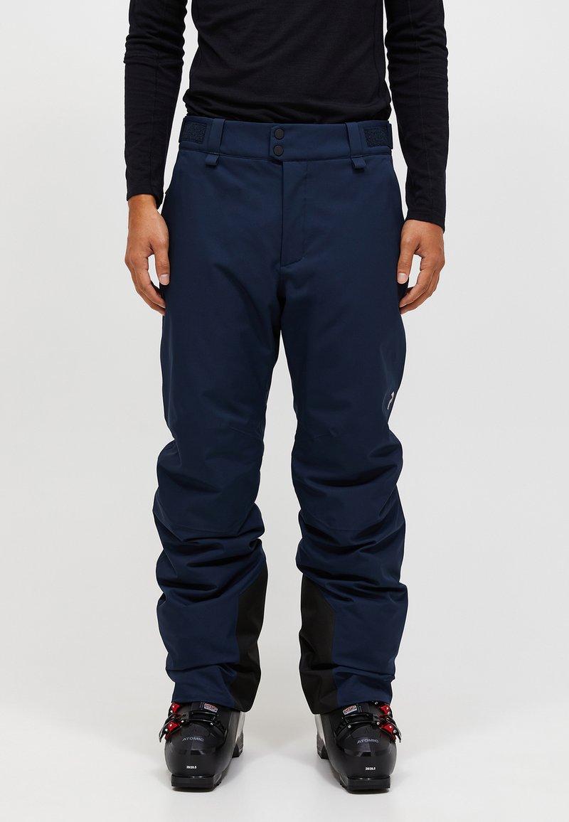 Marineblauwe skibroek met een losse pasvorm, voorzien van een gladde textuur, verstelbare taille met klittenband en zwarte accenten bij de enkels.