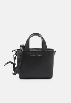 Kleine zwarte leren handtas met korte handvatten en verstelbare riem, met het "TOMMY JEANS" logo in zilveren letters aan de voorkant.