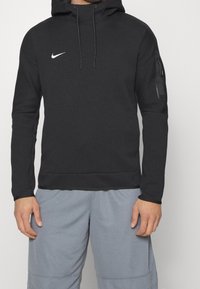 Felpa con cappuccio nera, dotata di tasca frontale e tasca laterale con zip. Realizzata in tessuto morbido, presenta un piccolo logo Nike bianco sul petto.