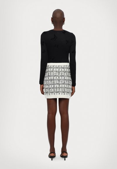 Black long-sleeve top with subtle butterfly patterns, paired with a fitted white and black textured checkered skirt with a ribbed hem.