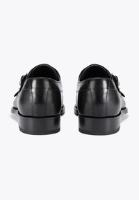 Czarne skórzane buty o gładkiej fakturze, okrągłym nosku, niskim obcasie i bocznym zapięciu. Czysty, minimalistyczny design, odpowiedni do strojów formalnych.