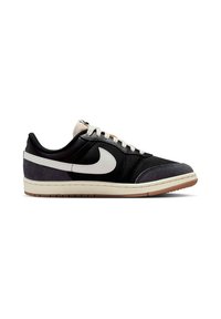 Μαύρο sneaker χαμηλού προφίλ με λευκή σόλα, λευκό λογότυπο Nike, λευκά κορδόνια και σκούρα γκρι σουέτ λεπτομέρειες στη μύτη και τη φτέρνα, πλάγια όψη.