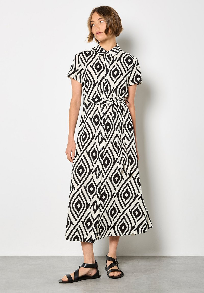 Schwarz-weißer, gemusterter Maxikleid mit einem kragenlosen Ausschnitt, kurzen Ärmeln und gebundenem Taillenbund. Es hat rautenförmige Motive und ein fließendes Design.