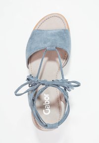 Blue suede sandal with a flat sole, open toe design, and decorative tie at the ankle. Features smooth inner lining and branded insole.