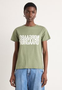 Olivgrünes Baumwoll-T-Shirt mit rundem Ausschnitt und kurzen Ärmeln, das auffälligen weißen Text mit der Aufschrift "NORGAARD" in umgekehrtem Stil zeigt.