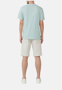 Jasno-niebieska koszulka z krótkim rękawem wykonana z miękkiego materiału, w połączeniu z jasnobeżowymi szortami. Prosty design z okrągłym dekoltem i bez widocznych wzorów.