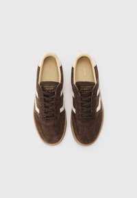 Sneaker in suede marrone con strisce in pelle bianca e lacci marroni. Presentano una punta arrotondata e suola in gomma testurizzata. Marchio dorato all'interno.