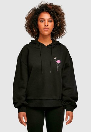 Czarna, oversize bluza z kapturem wykonana z miękkiego materiału, zdobiona grafiką różowej flamingo na klatce piersiowej, z przednią kieszenią typu kangur i sznurkiem do ściągania w kapturze.