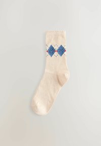 Beige Sock mit blauen Rautenmustern und kleinen Blumenmotiven, auf einem hellen Hintergrund präsentiert.