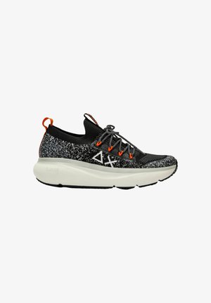 Zwarte en grijze sport schoenen met een gestructureerde bovenkant, voorzien van een oranje hielstrip, dikke witte zool en een kenmerkend grafisch ontwerp.