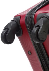 Rode hardcase koffer met een gestructureerd oppervlak, zwarte ritsen en dubbele 360-graden spinnerwielen voor gemakkelijke wendbaarheid.