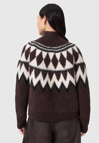 Maglione marrone in lana con collo alto, caratterizzato da un motivo geometrico bianco e nero sulla spalla e polsini e orlo a costine.