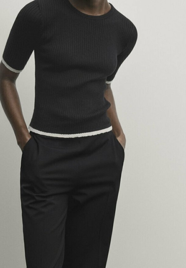 Top a coste nera a maniche corte con bordi bianchi ai polsini e all'orlo, abbinato a pantaloni neri su misura.