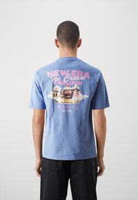 Světle modré bavlněné tričko s grafickým potiskem zmrzlinového poháru a textem "NEW ERA Ice Cream Parlour Miami FL Est. 1920" na zádech.