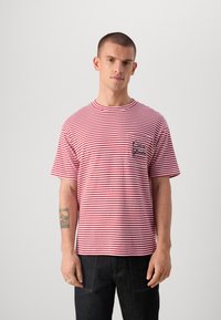 Rød og hvitstripet t-skjorte med kort erme, rund hals, og en frontlomme med svart skriftskrift design. Laget av bomull.