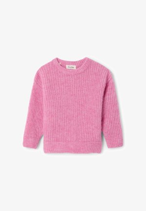 Pull en maille rose avec texture côtelée, pantalon de survêtement gris coordonné, et baskets blanches avec semelles marron et accents bleus, fille debout.