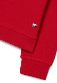 Rode sweatshirt met ribgebreide manchetten en een zilveren hartvormig logo op de zijkant, gemaakt van een zachte, geweven stof.