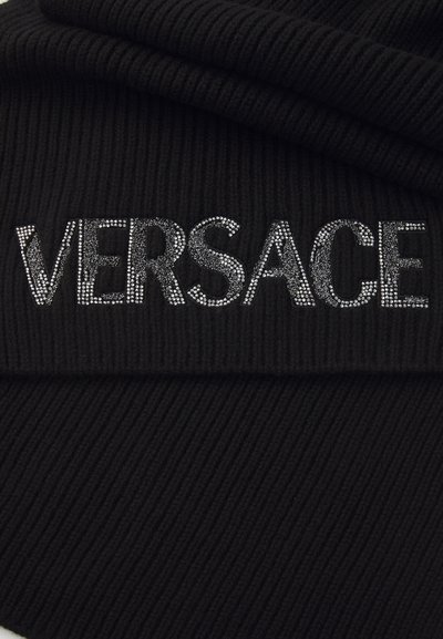 Schwarzer gerippter Strickstoff mit dem Schriftzug "VERSACE", verziert mit silbernen Strasssteinen. Das Design hat eine gefaltete Struktur mit vertikalen Linien.