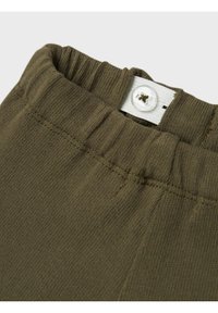 Pantalon en mélange de coton vert olive avec une taille élastique, doté d'un bouton blanc et d'une texture légèrement côtelée au niveau de la taille.