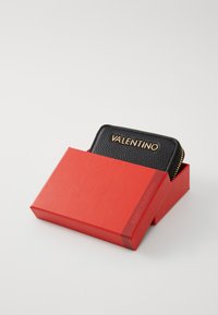 Must mustril nahkrahakott kuldse "VALENTINO" logoga, esitatud punases karbis. Rahakotil on lukuga sulgemine ja kompaktne ristkülikukujuline kuju.