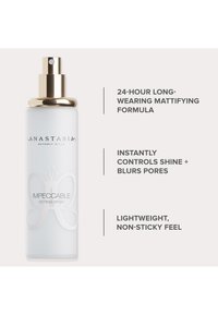 Transparante spuitfles met een gouden pompdeksel; heeft een vlinderontwerp en glanzende tekst op een matte oppervlakte. Bevat instelspray voor make-up.
