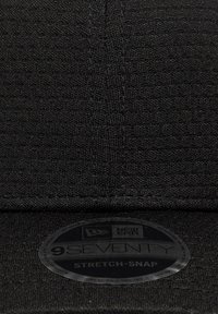 Μαύρο καπέλο μπέιζμπολ με υφασμάτινη υφή, που διαθέτει στρογγυλεμένη γείσο και στρογγυλή ετικέτα New Era με τις λέξεις "9SEVENTY" και "STRETCH-SNAP".