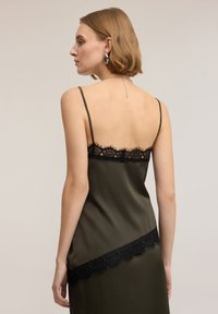 Vestito in raso verde oliva con rifiniture in pizzo nero lungo lo scollo e l'orlo. Caratterizzato da spalline sottili e una texture liscia e lucida.