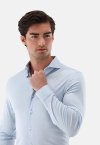 Hellblaues Langarmhemd mit Button-Down-Kragen, tailliertem Schnitt, glatter Textur und kontrastierenden Akzenten an Innenkragen und Manschetten.