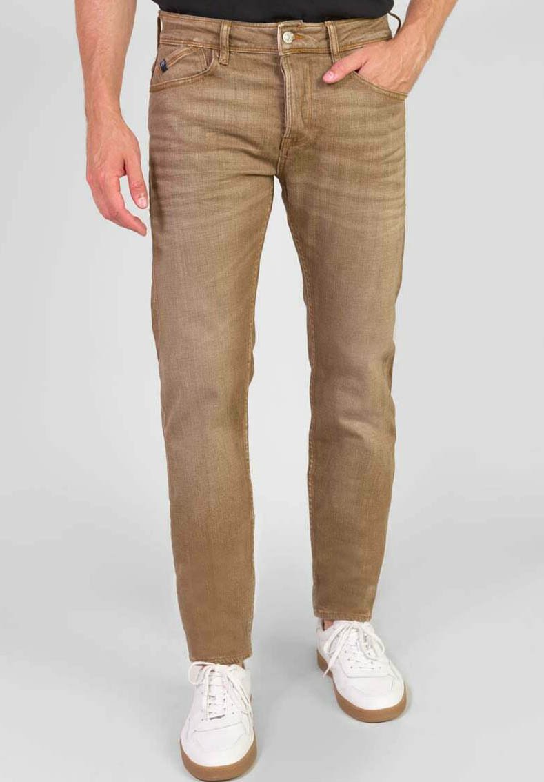 Beige spijkerbroek met een rechte pijp, subtiele textuur, vijfzakkenontwerp en metalen knoopsluiting; gedragen met witte sneakers.