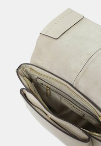 Borsa a mano in pelle beige con esterno in suede testurizzato, dotata di cerniere oro e molteplici tasche interne per l'organizzazione.