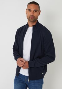 Maglione zip-up blu navy realizzato in morbido materiale a maglia, con colletto alto, polsini a coste e un delicato accento con logo sull'orlo.